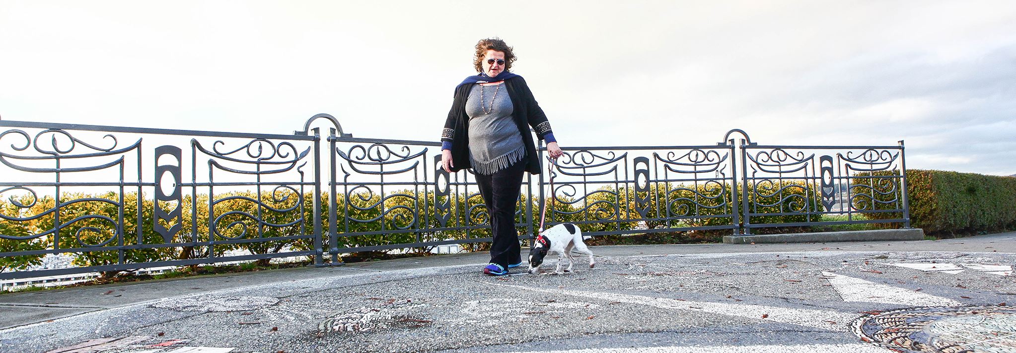 Woman and dog walk along Grand Ave park.